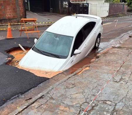 Asfalto cede durante temporal e carro é engolido por cratera